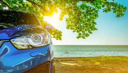A Nelson's hire car parked under a tree beside a turquoise Seychelles beach
